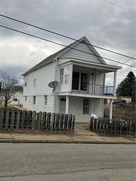 view of front of house featuring a balcony and a fenced front yard