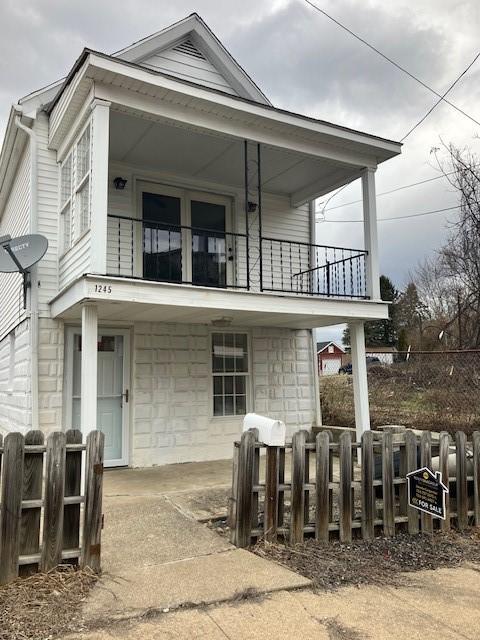 back of house with a balcony and fence