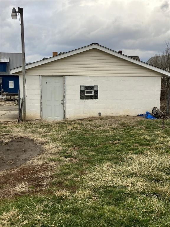 view of side of property featuring concrete block siding and a yard