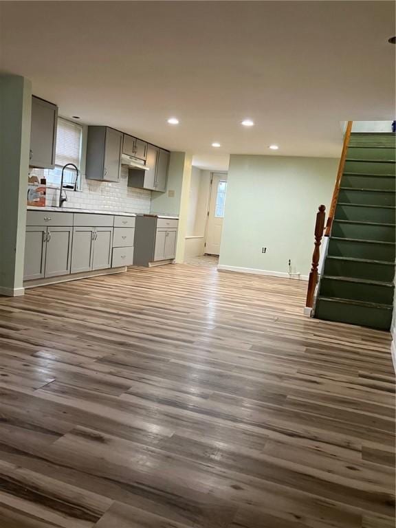 kitchen with recessed lighting, gray cabinetry, wood finished floors, baseboards, and decorative backsplash