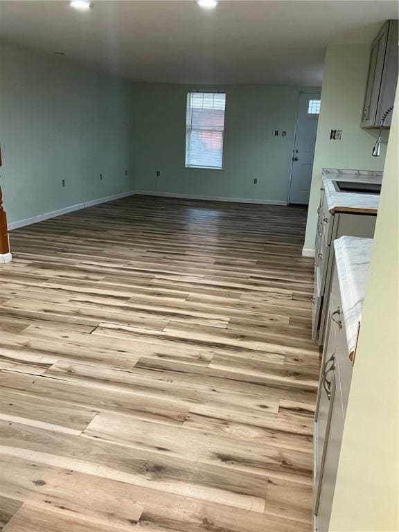 kitchen with open floor plan, light countertops, wood finished floors, and baseboards