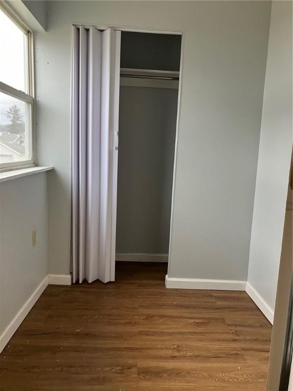 unfurnished bedroom with a closet, baseboards, and wood finished floors