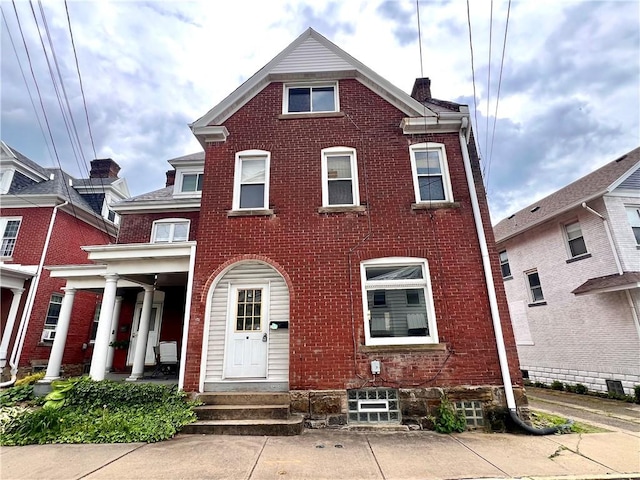 view of front of property with entry steps, brick siding, and a chimney