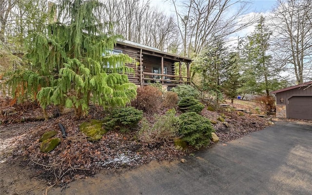 view of front of property featuring a garage, aphalt driveway, and log siding