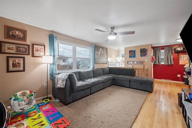 living room with ceiling fan, light wood-style flooring, visible vents, and baseboards