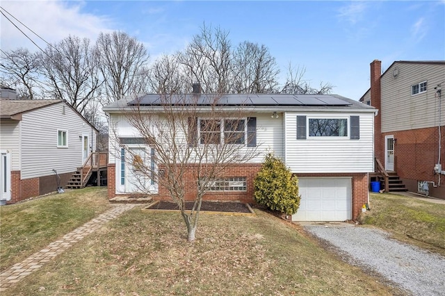 view of front of property with brick siding, solar panels, a front yard, a garage, and driveway