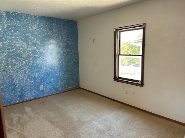 spare room with carpet, baseboards, and wallpapered walls