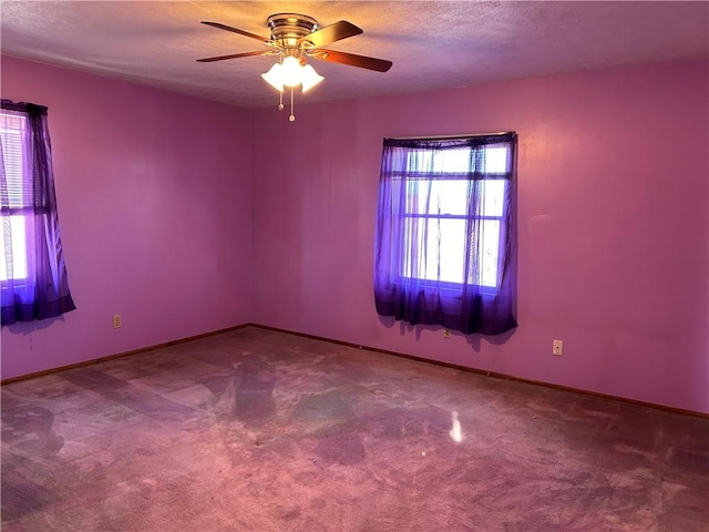 carpeted empty room with a textured ceiling, a ceiling fan, and baseboards