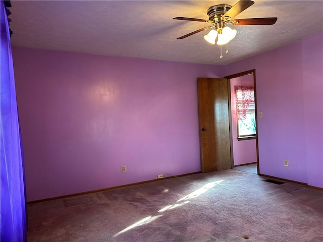 empty room with a textured ceiling, carpet, visible vents, and baseboards