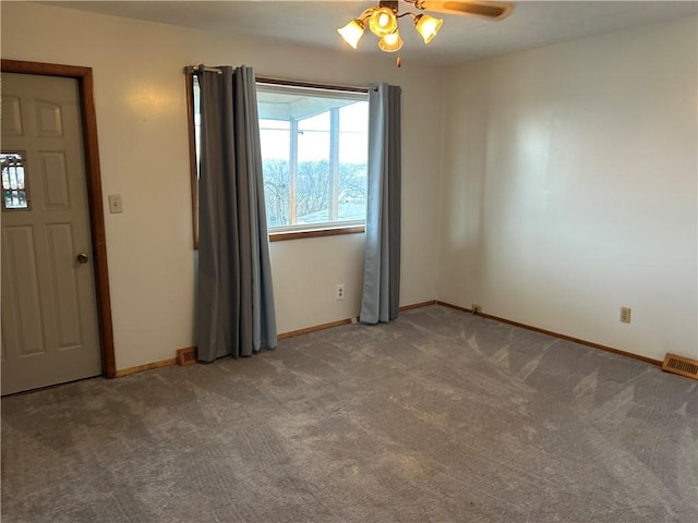 carpeted spare room featuring a ceiling fan, visible vents, and baseboards