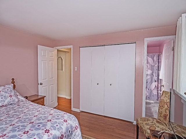 bedroom with a closet, baseboards, and wood finished floors