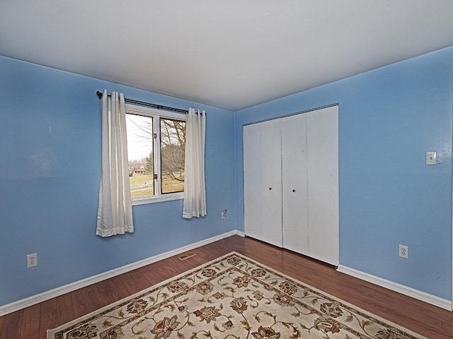 unfurnished bedroom featuring wood finished floors, visible vents, and baseboards