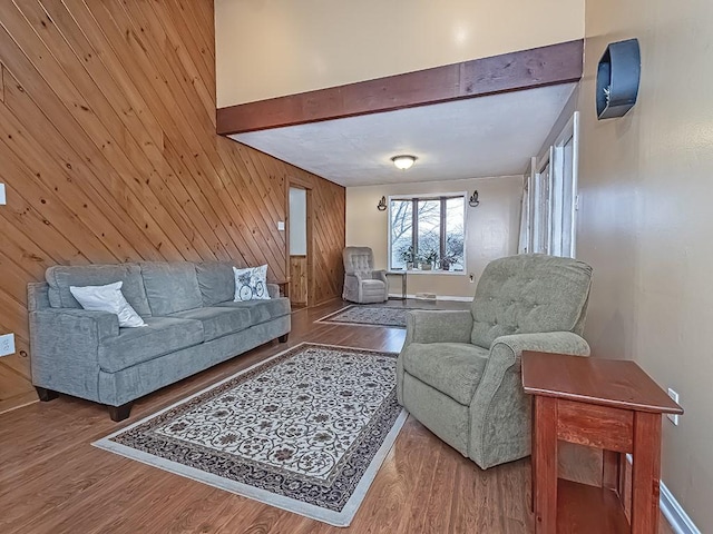 living room featuring wood walls, beam ceiling, and wood finished floors