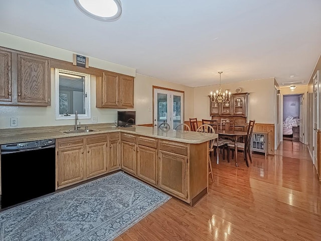 kitchen featuring dishwasher, a peninsula, light countertops, light wood-type flooring, and a sink