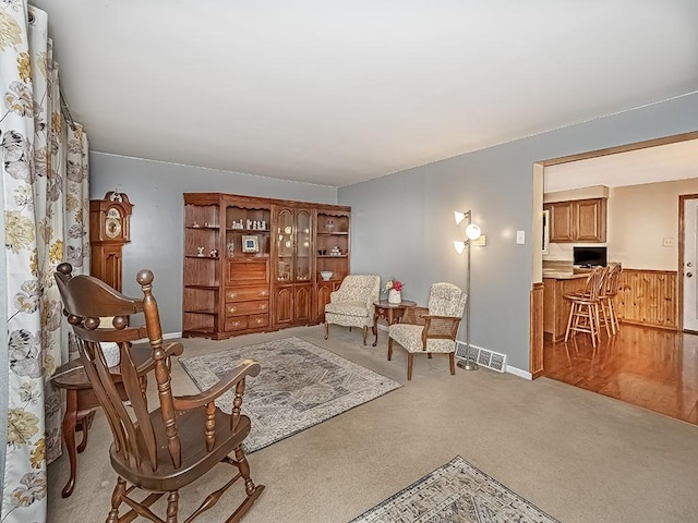 sitting room with wood walls, wainscoting, carpet flooring, and visible vents