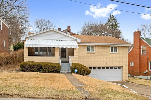 view of front of home with a garage, concrete driveway, a chimney, a front lawn, and brick siding