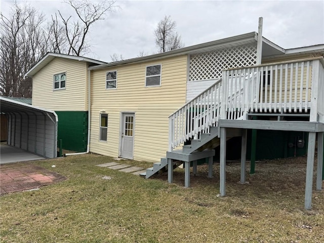 back of house with a detached carport, a yard, and stairs