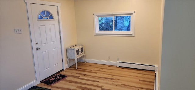 foyer entrance with baseboard heating, light wood-type flooring, and baseboards