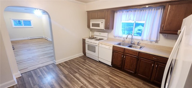 kitchen with arched walkways, white appliances, wood finished floors, a sink, and light countertops