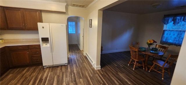 kitchen with arched walkways, a baseboard heating unit, white refrigerator with ice dispenser, visible vents, and dark wood-style floors