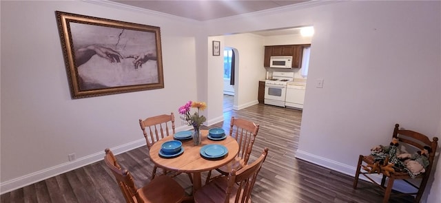 dining area with crown molding, arched walkways, dark wood finished floors, and baseboards