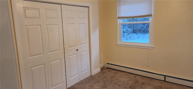 unfurnished bedroom featuring carpet, baseboard heating, and a closet