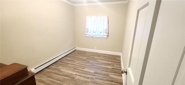 empty room featuring a baseboard heating unit, ornamental molding, baseboards, and wood finished floors