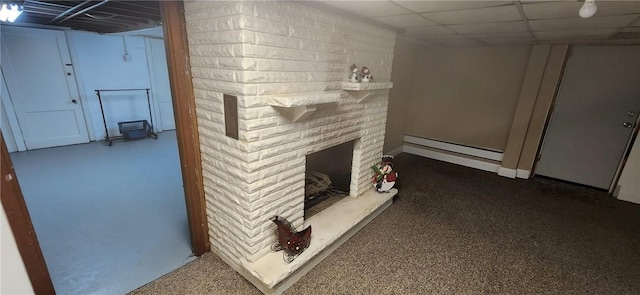 interior space featuring a baseboard heating unit, a large fireplace, and a drop ceiling