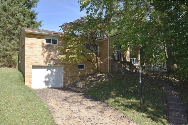 view of home's exterior with driveway, an attached garage, fence, a yard, and brick siding