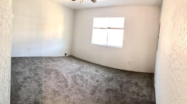 carpeted spare room featuring visible vents and ceiling fan