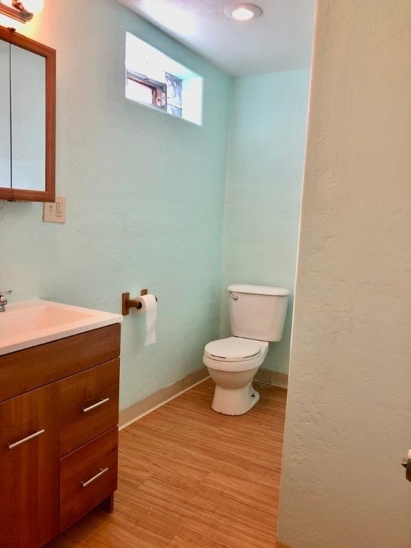 bathroom featuring vanity, wood finished floors, toilet, and baseboards