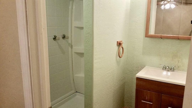 bathroom with a textured wall, a shower stall, and vanity