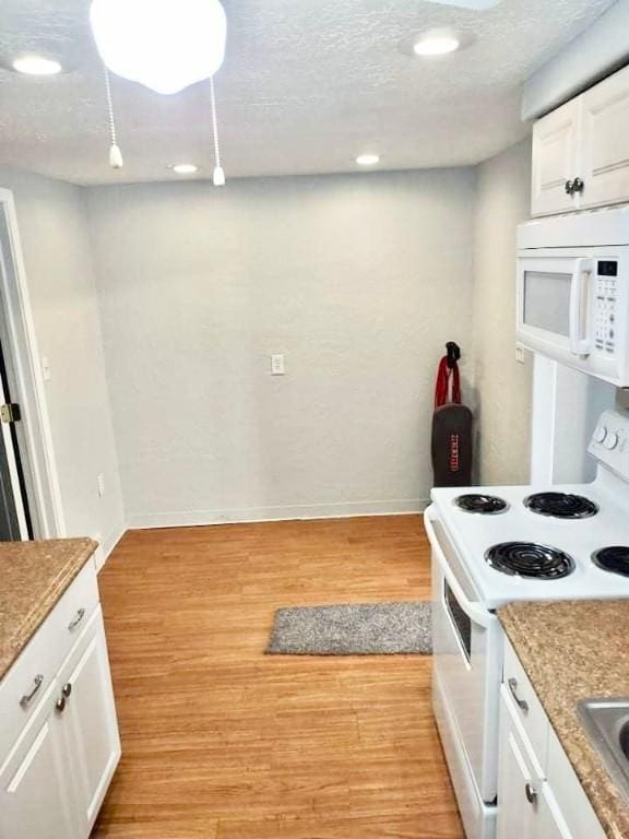 kitchen with light wood-style floors, white cabinetry, a textured ceiling, white appliances, and baseboards