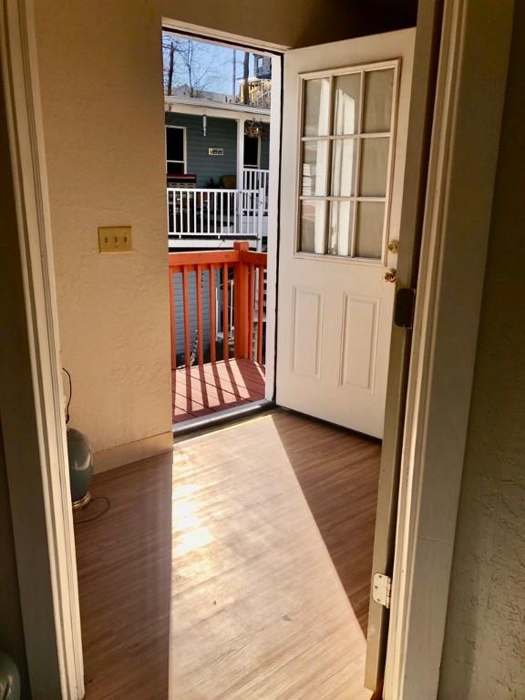 doorway with a textured wall and wood finished floors