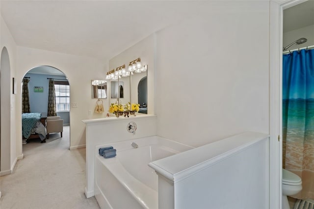 ensuite bathroom featuring ensuite bath, a garden tub, toilet, and baseboards