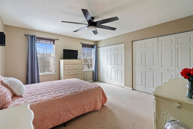 carpeted bedroom with baseboards, a ceiling fan, and multiple closets