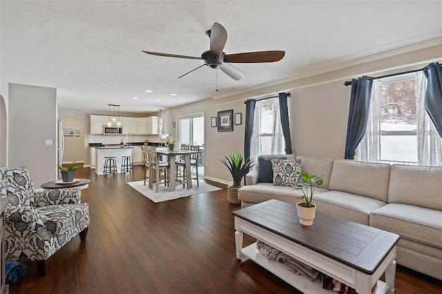 living area with ceiling fan, baseboards, dark wood finished floors, and a textured ceiling