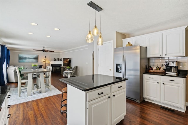 kitchen with dark countertops, stainless steel fridge, a fireplace, and decorative backsplash