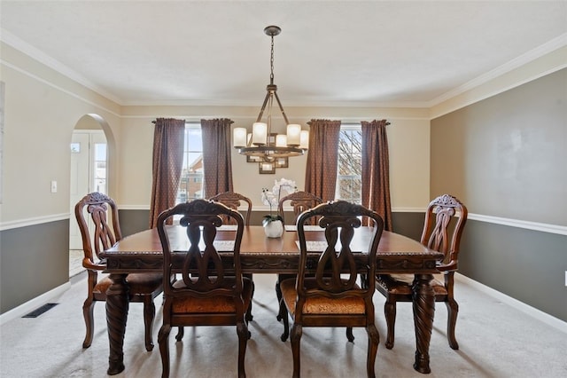 dining space with light carpet, plenty of natural light, and arched walkways