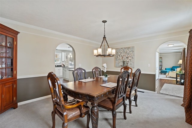 dining space featuring arched walkways, ornamental molding, light carpet, and baseboards