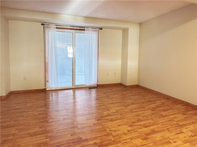 unfurnished room with light wood-style flooring and baseboards