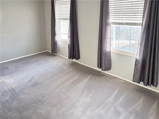 empty room with carpet, a healthy amount of sunlight, and baseboards