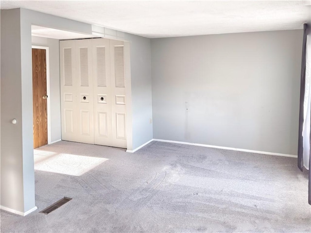 unfurnished bedroom with carpet, baseboards, visible vents, and a closet