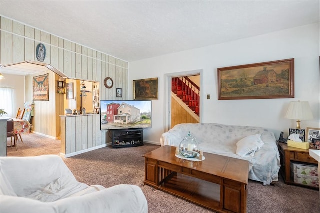 living room featuring carpet floors, baseboards, and stairs