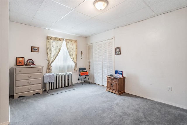 carpeted bedroom featuring a closet, a drop ceiling, and radiator heating unit