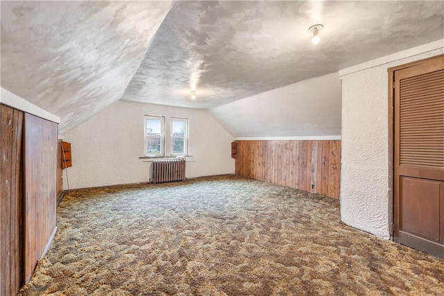 bonus room with lofted ceiling, a textured ceiling, a textured wall, carpet floors, and radiator heating unit