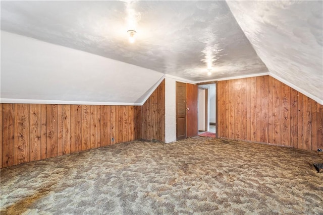 additional living space with lofted ceiling, wooden walls, and carpet flooring