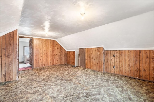 additional living space with carpet floors, wood walls, and vaulted ceiling