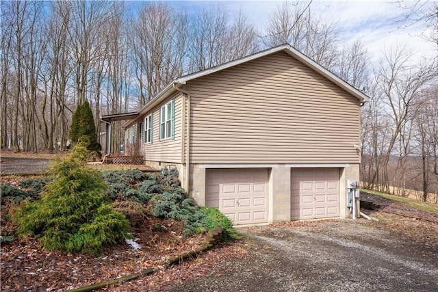 view of side of home featuring a garage and dirt driveway