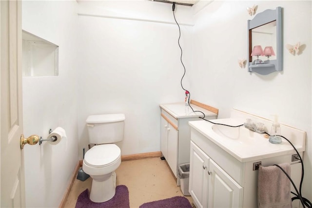 half bath featuring toilet, vanity, and baseboards